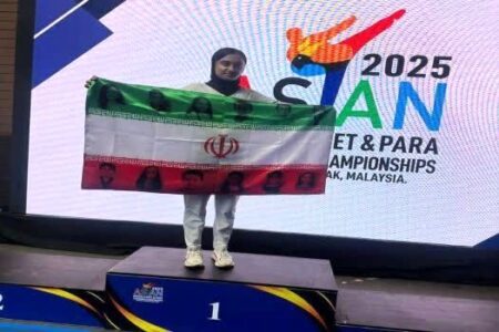 ‌دانش‌آموز مدال‌آور ایرانی با پرچم شهدای کودک بر روی سکوی قهرمانی رفت